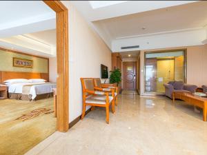a hotel room with a bed and a living room at Vienna International Hotel Shenzhen Longgang Lilang in Longgang