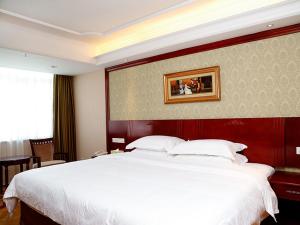 een groot wit bed in een hotelkamer bij Vienna Hotel Shenzhen Futian Bagua Road in Shenzhen