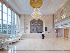 eine Person steht in einer großen Lobby mit einem großen Gemälde in der Unterkunft vienna Hotel (fujian quanzhou dehua station) in Dehua