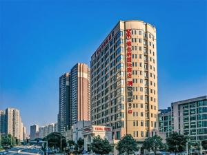 ein hohes Gebäude in einer Stadt mit vielen Gebäuden in der Unterkunft Vienna Hotel (Mulian West Road Shop, Changsha) in Changsha