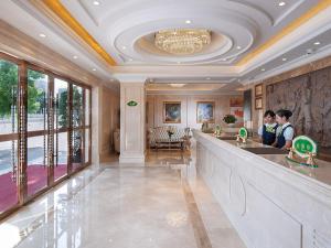 twee personen staan aan een bar in een grote kamer bij Vienna Hotel Shenzhen Guanlan Renming Road Heping in Tiantangwei