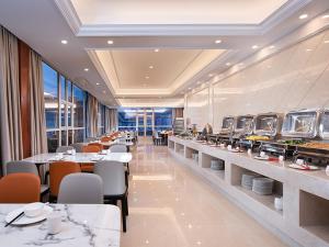 Gaozhou的住宿－維也納酒店廣東高州城東客運站店，一间带桌椅的用餐室和一间自助餐厅