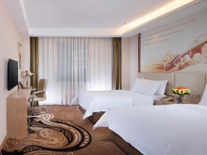 Vienna Hotel (East Plaza of WuHan High-Speed Railway Station) في ووهان: غرفه فندقيه سريرين وتلفزيون