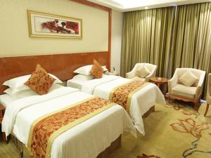 una camera d'albergo con due letti e due sedie di Vienna Classic Hotel Kongtong Avenue a Pingliang