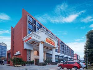 a red car parked in front of a building at Vienna International Hotel Nanjing Hehai University Station in Zhucun