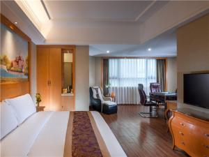 a hotel room with a large bed and a flat screen tv at Vienna International Hotel (Shen Zhen Buji Dafen shop) in Shenzhen