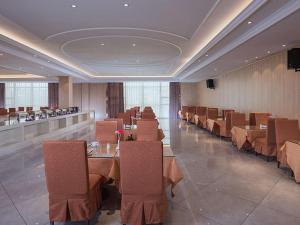 a dining room with tables and chairs in a restaurant at Vienna Hotel (Shajinbei Road Fuquan Guizhou) in Fuquan