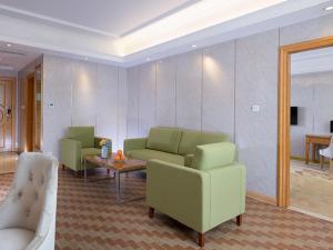a living room with two green couches and a table at Vienna Hotel HaiNan Oriental Avenue in Dongfang +4 photos