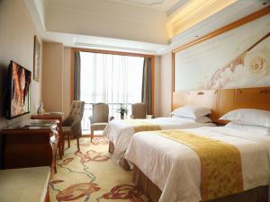 Una habitación de hotel con dos camas y un escritorio. en Vienna International Hotel Changsha West Bus Station, en Changsha