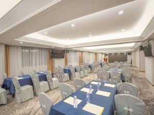 a banquet hall with blue tables and chairs and a screen at Venus royal hotel(Keyuan Guancheng Dongguan) in Dongguan