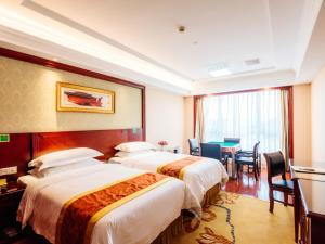 a hotel room with three beds and a dining room at Vienna Hotel Shanghai Wild Animal Park in Nanhui