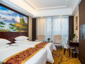 Vienna International Hotel(Hangzhou Xiasha University City) في هانغتشو: غرفة فندقية بسريرين ولوحة على الحائط
