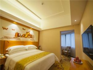 Pokój hotelowy z dużym łóżkiem i telewizorem w obiekcie Vienna Hotel Yulin Jincheng Zhenlin w mieście Yulin