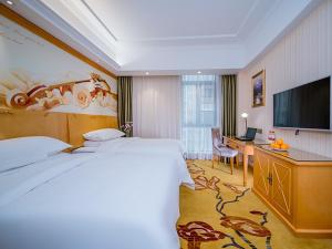 a hotel room with a bed and a desk and a television at Vienna Hotel Whhan xingye road stone bridge subway station store in Wuhan