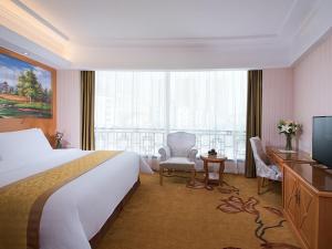 ShengzhouにあるVienna Hotel (Shengzhou Bada Hotel)のベッドと大きな窓が備わるホテルルームです。