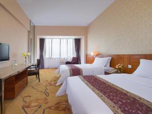 a hotel room with two beds and a desk at Vienna International Hotel - Foshan Haiyue Branch in Nanhai