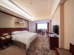 una camera d'albergo con un grande letto e una TV di Vienna Classic Hotel Shizhongshan Avenue a Jiujiang