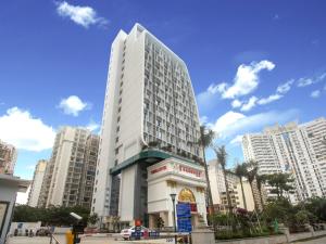 a tall white building in a city with tall buildings at Vienna International Hotel Haikou West Bus Station in Haikou