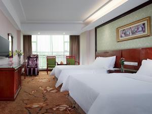 a large hotel room with two beds and a desk at Vienna Hotel Huizhou Zhongxin in Huizhou