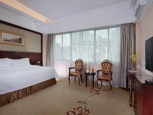 um quarto de hotel com uma cama e duas cadeiras e uma mesa em Vienna Hotel Nanning Changhu Road em Nanning