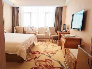 ein Hotelzimmer mit einem Bett und einem Schreibtisch in der Unterkunft Vienna Hotel Liaocheng University in Liaocheng