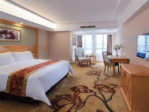 Pokój hotelowy z dużym łóżkiem i telewizorem w obiekcie Vienna International Hotel Zhongshan Torch Development Zone w mieście Zhongshan