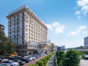 un gran edificio con coches estacionados en un estacionamiento en Vienna 3 Best Hotel Shenzhen Henggang Cuihu Shangzhuang en Longgang