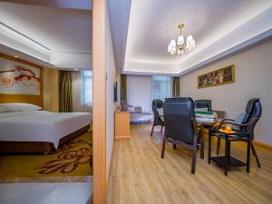 um quarto de hotel com uma cama, uma secretária e cadeiras em Vienna Hotel Whhan xingye road stone bridge subway station store em Wuhan