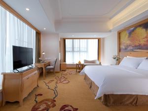 a hotel room with a bed and a flat screen tv at Vienna International Hotel Shenzhen Hua'nan City in Longgang +15 photos