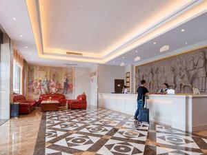 een man aan een balie in een hotellobby bij Vienna 3 Best Hotel Dongguan Shida Road in Liaobu
