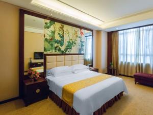 a hotel room with a large bed and a large window at Vienna Hotel Lufeng Peopole Road in Lufeng