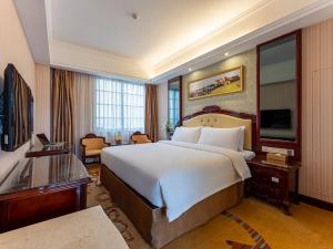 a hotel room with a large bed and a television at Vienna Hotel Jingxi Zhongshan Park in Jingxi