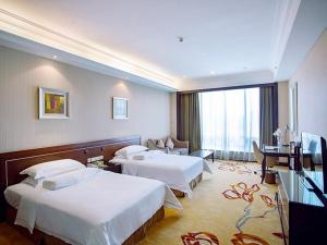 a hotel room with two beds and a television at Vienna International Hotel Shenzhen Hua'nan City in Longgang