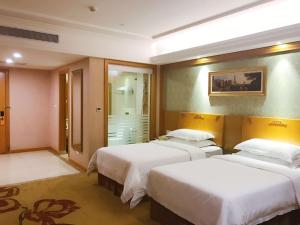 a hotel room with three beds and a bathroom at Vienna Hotel Foshan Nanzhuang Avenue in Foshan