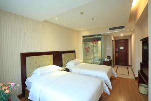 Postel nebo postele na pokoji v ubytování Vienna Hotel in Pinghu Square + 4 fotografie