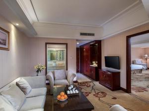 uma sala de estar com um sofá e uma televisão num quarto em Vienna Hotel Shaoguan Wujiang Kuangshan Park em Shaoguan