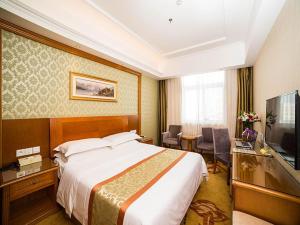a hotel room with a bed and a flat screen tv at Vienna Hotel Shandong Yantao Golden Beach Taishan Road in Yantai