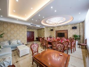 a dining room with a table and chairs and a couch at Vienna International Hotel Shanghai Hongqiao Exibition Central Xinqiao in Chunshen