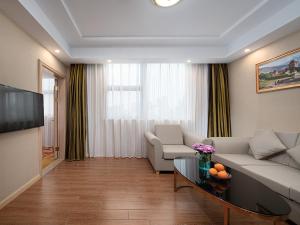 a living room with a couch and a table at Vienna Hotel(Ganzhou Railway Station Shop) in Ganzhou +2 photos