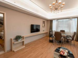 a living room with a dining table and a television at Vienna International Hotel (Hunan Changde Taoyuan Longba) in Taoyuan