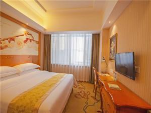 a hotel room with a bed and a flat screen tv at Vienna Hotel Yulin Jincheng Zhenlin in Yulin