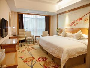 a hotel room with a large bed and a desk at Vienna Hotel Ganzhou Anyuan in Tieshan