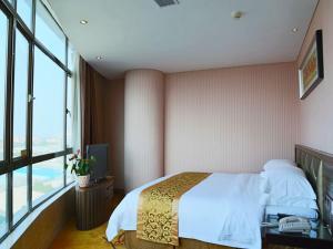 een slaapkamer met een bed en een groot raam bij Vienna 3 Best Hotel Dongguan Shida Road in Liaobu