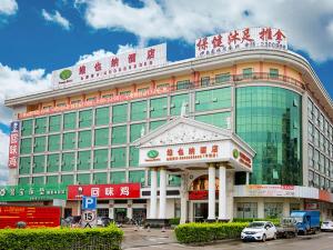 a large building with a car parked in front of it at Vienna Hotel Huizhou Zhongxin in Huizhou