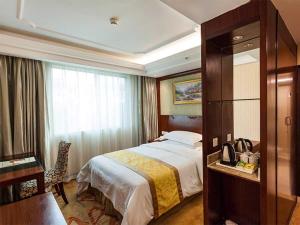 Cette chambre comprend un lit, un bureau et une fenêtre. dans l'établissement Vienna Hotel Nanjing Longjiang, à Nankin
