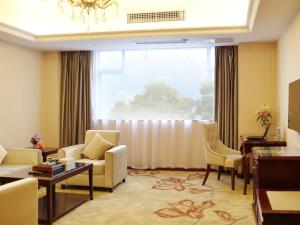 a living room with a couch and chairs and a large window at Vienna Hotel Foshan Nanhai City Square in Foshan