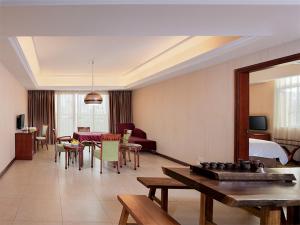 una sala de estar con una habitación con una cama y una mesa en Vienna Hotel Dongguan Hou street Wanda Plaza, en Dongguan