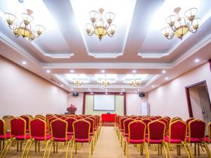 una sala de conferencias con sillas rojas y una pantalla en Vienna International Hotel Huizhou South Railway Station, en Huizhou