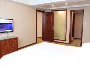 una habitación con TV y una habitación con puerta en Vienna International Hotel Ningbo South Huancheng Road, en Ningbo