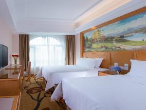 una camera d'albergo con due letti e un dipinto sul muro di Vienna Hotel Shenzhen Dalang Clothing Base a Bao'an